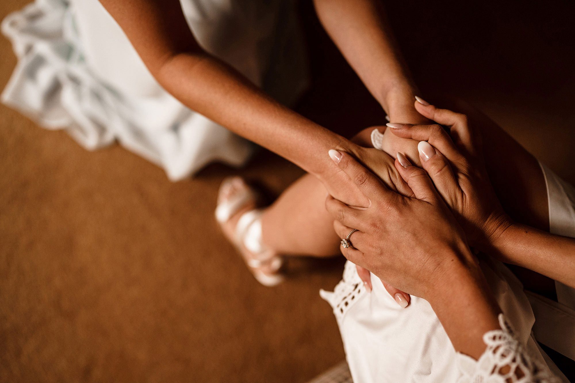 Bridesmaid placing her hands on the bride during preparations at a Cotswolds wedding
