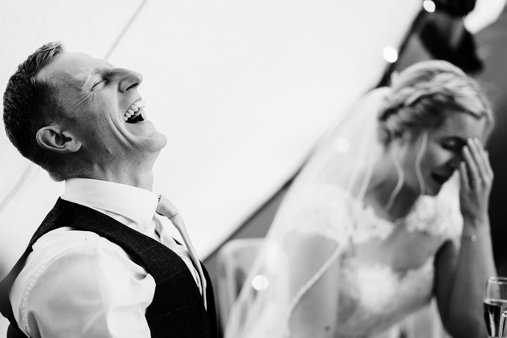 Groom laughing during speeches at a Cotswolds wedding
