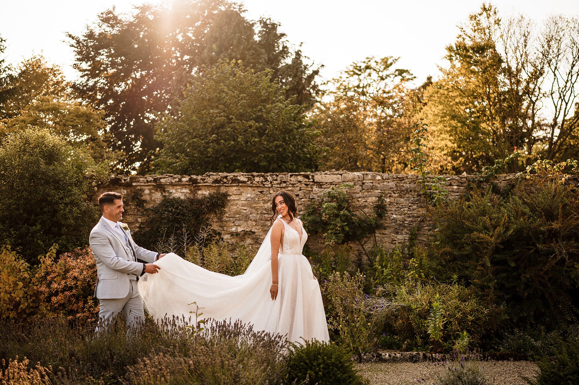 Groom holding the bride's dress during a Cotswolds wedding at Caswell House