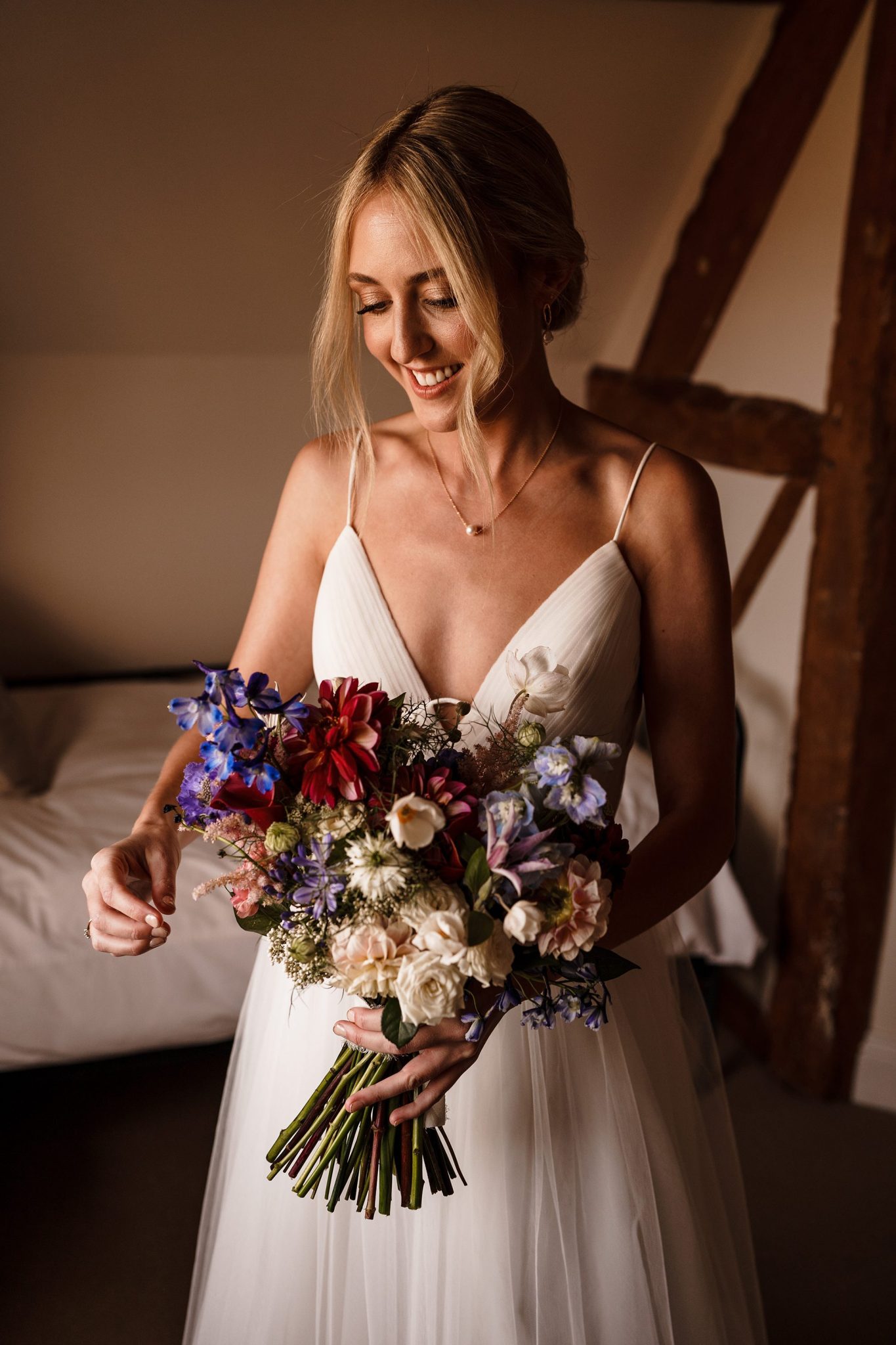 Bride holding bouquet in soft window light during wedding morning preparations
